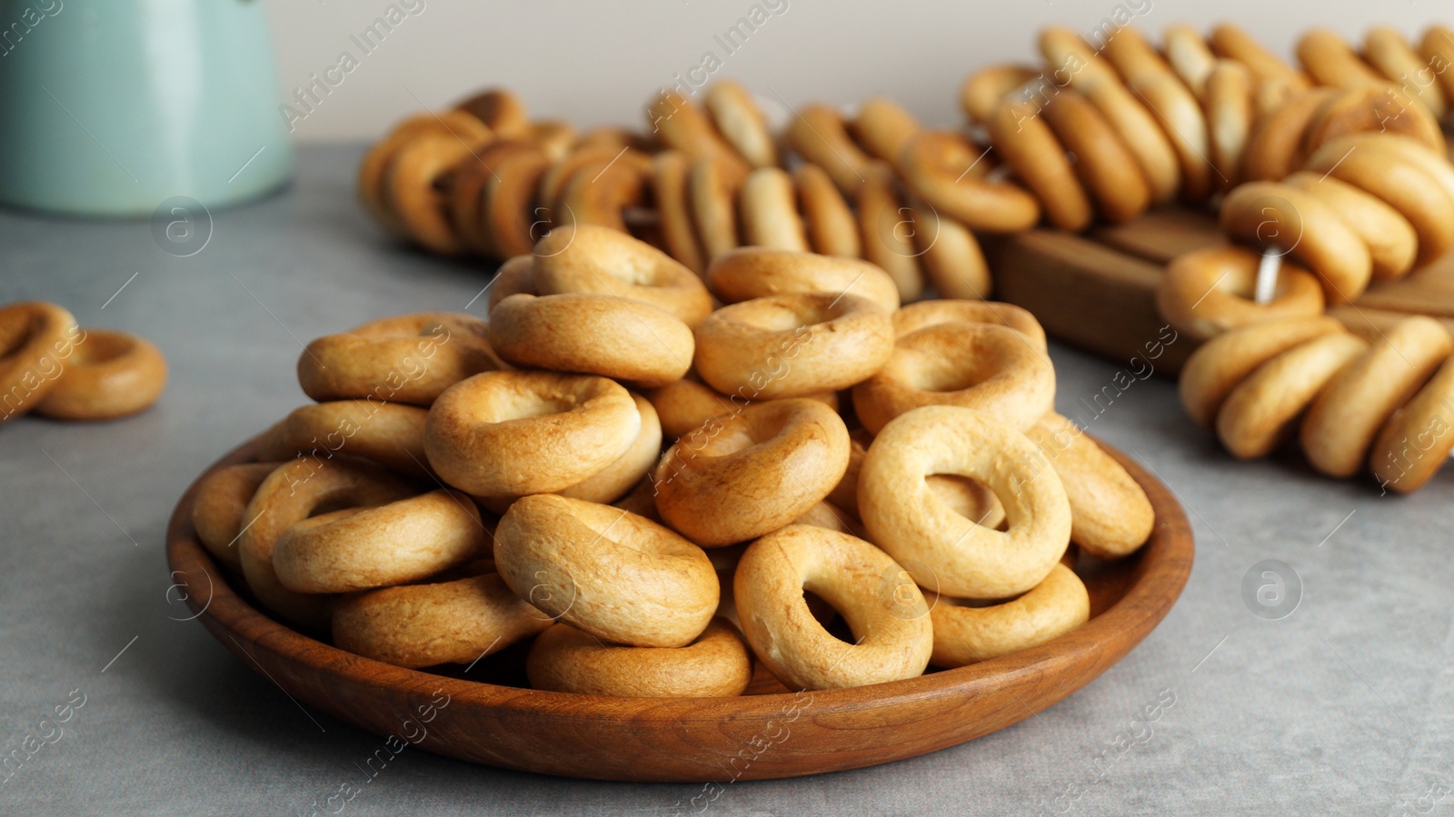 Photo of Plate with delicious ring shaped Sushki (dry bagels) on light grey table, closeup