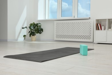 Exercise mat and yoga block on floor in room