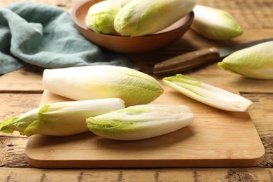 Photo of Fresh raw Belgian endives (chicory), board and knife on wooden table