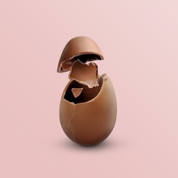 Image of Exploded milk chocolate egg on pale light pink background