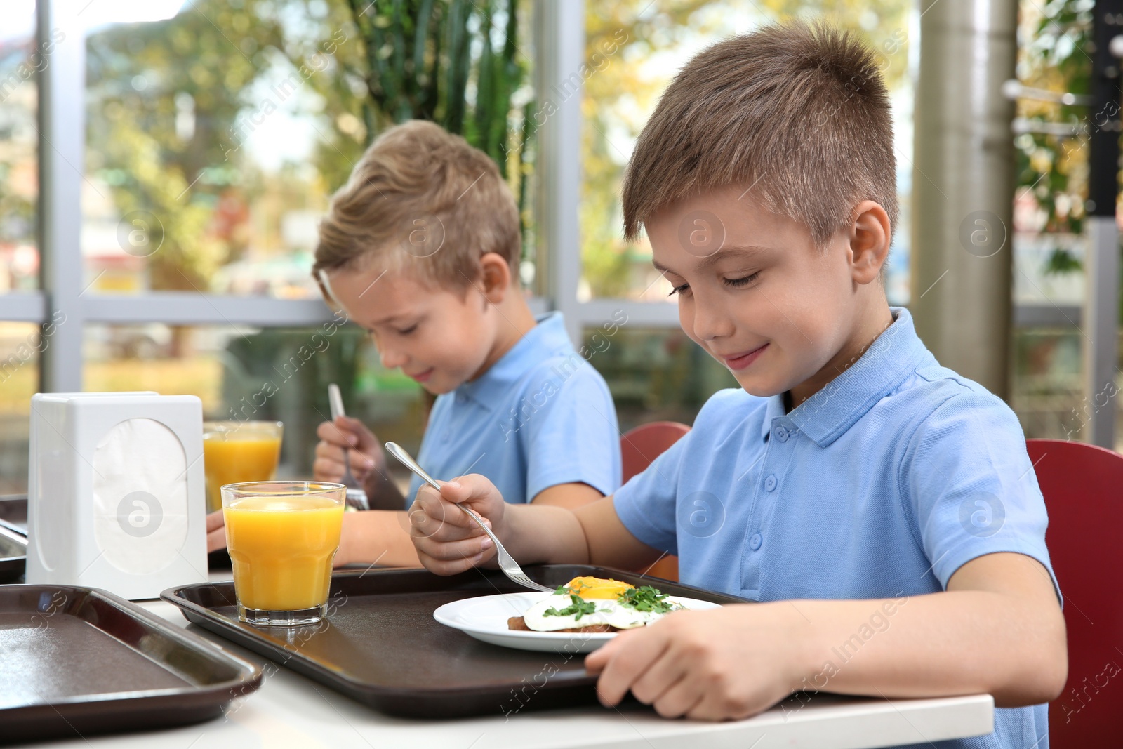 Photo of Cute children at table with healthy food in school canteen