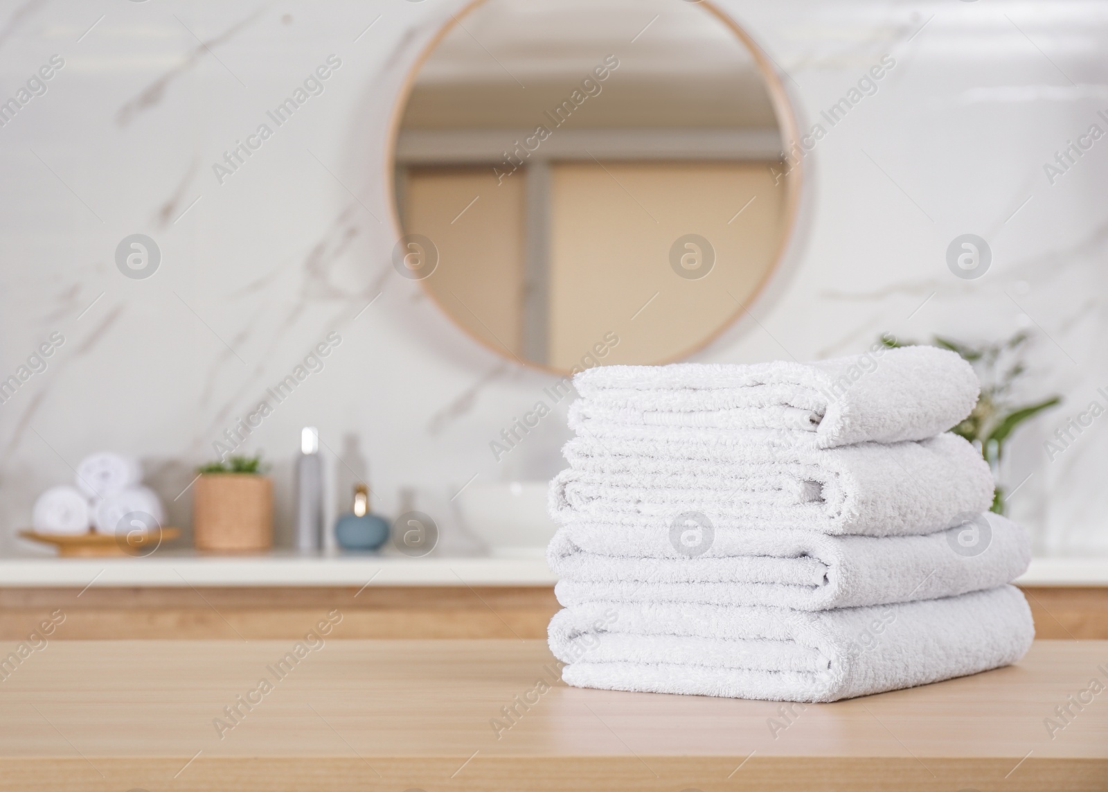 Photo of Stack of white towels on wooden table in bathroom. Space for text