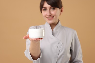 Cosmetologist with cosmetic product on beige background, selective focus