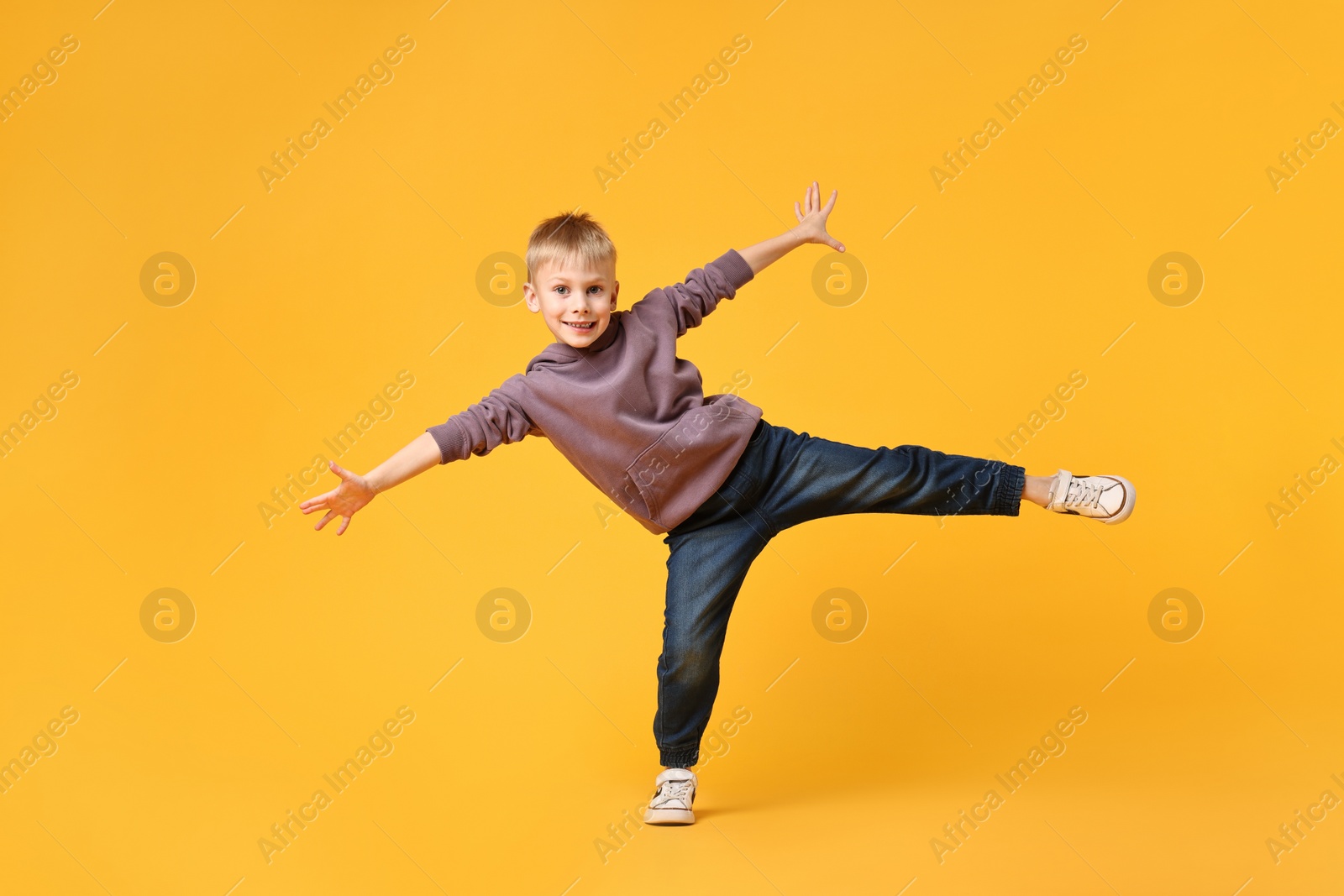 Photo of Happy little boy dancing on yellow background