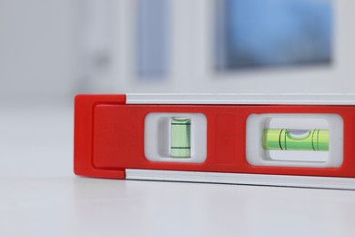 Photo of Red building level on white windowsill indoors, closeup