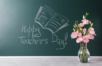 Photo of Green chalkboard with inscription HAPPY TEACHER'S DAY and vase of flowers on grey stone table