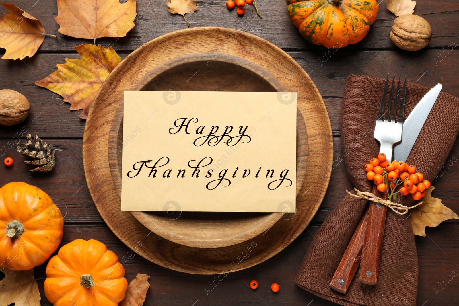 Image of Seasonal table setting with Happy Thanksgiving Day card and pumpkins on wooden table, flat lay