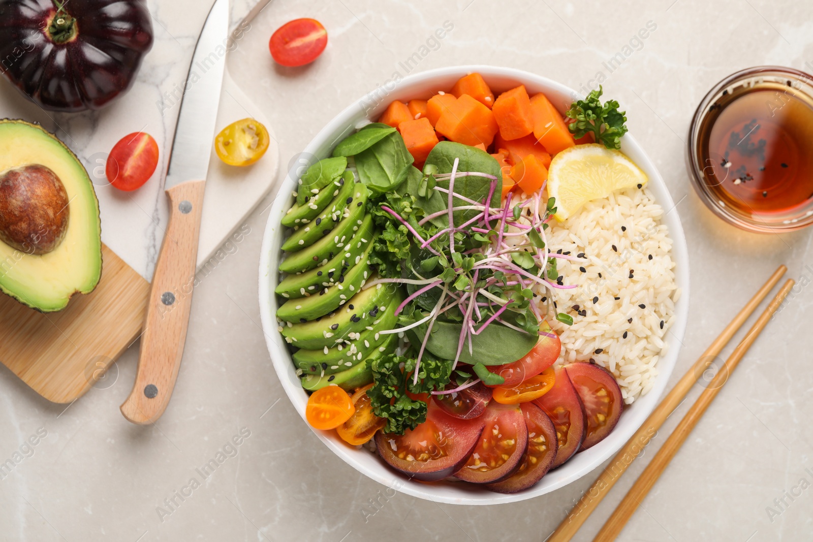 Photo of Delicious vegan bowl with avocados, carrots and tomatoes on light grey table, flat lay