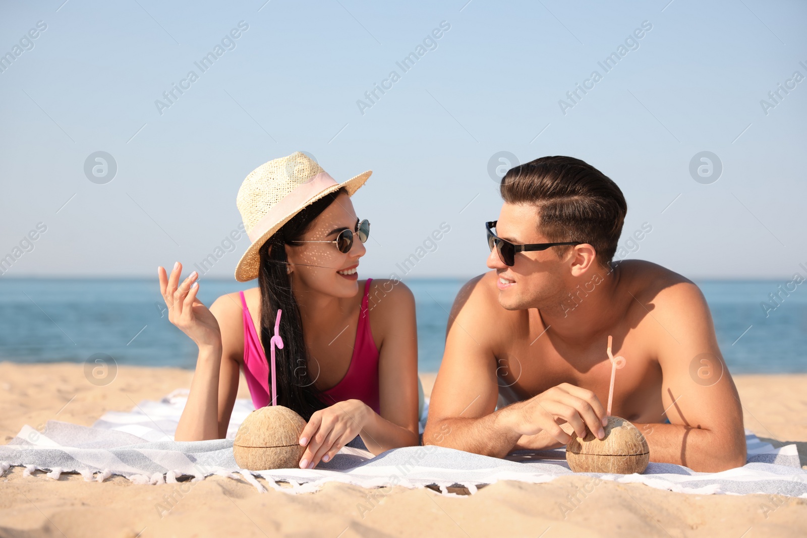 Photo of Happy couple with cocktails on sunny beach at resort