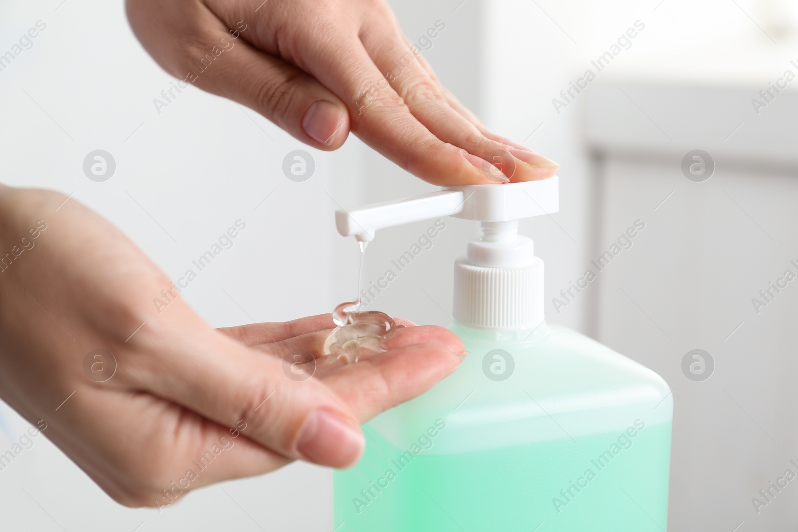 Photo of Woman applying antiseptic gel on hand indoors, closeup