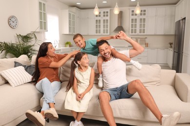 Photo of Happy family with children having fun on sofa at home