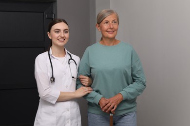 Photo of Young healthcare worker assisting senior woman indoors