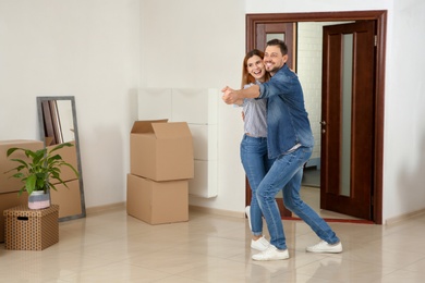 Couple dancing near moving boxes in their new house