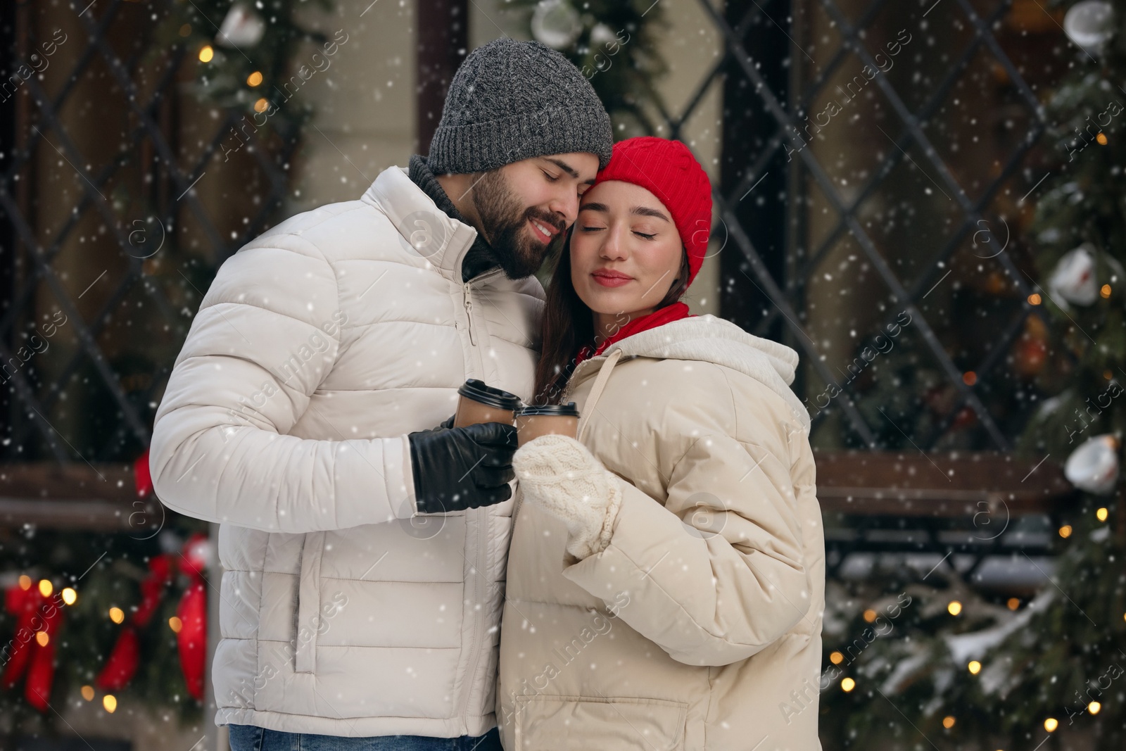 Photo of Lovely couple with hot drinks spending time together on city street