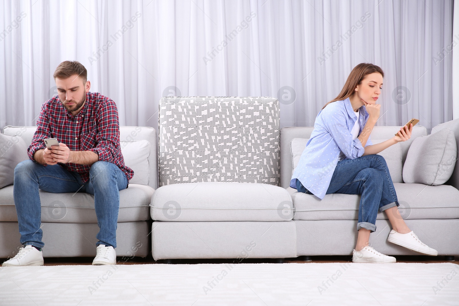 Photo of Couple addicted to smartphones ignoring each other at home. Relationship problems