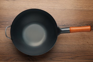 Photo of Empty iron wok on wooden table, top view. Chinese cookware