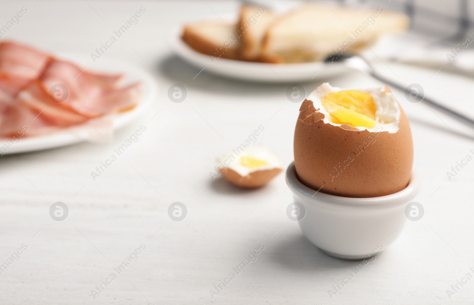 Photo of Holder with soft boiled egg on table. Space for text