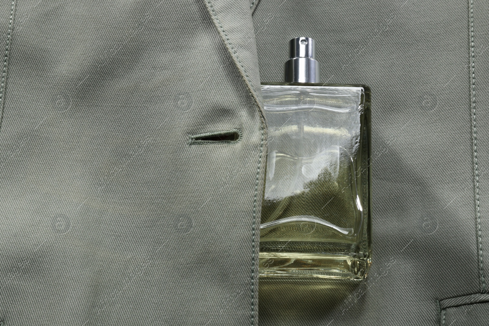 Photo of Luxury men's perfume in bottle on grey jacket, top view. Space for text