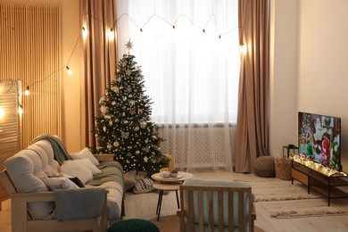 Photo of Wide TV set, furniture and Christmas tree in stylish room