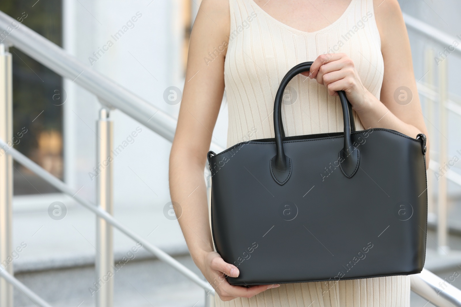 Photo of Young woman with stylish leather bag on stairs outdoors, closeup