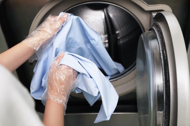 Photo of Young woman loading washing machine in dry-cleaning, closeup