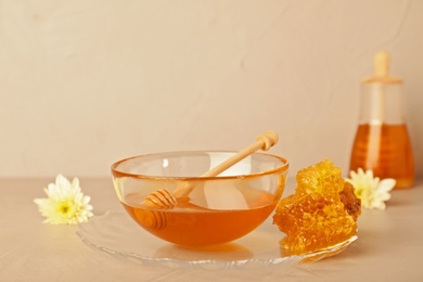 Glass bowl with tasty honey and dipper on table