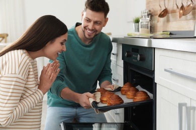 Couple baking buns in oven at home