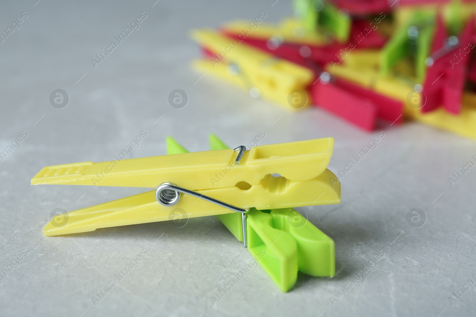 Photo of Colorful plastic clothespins on grey table, closeup