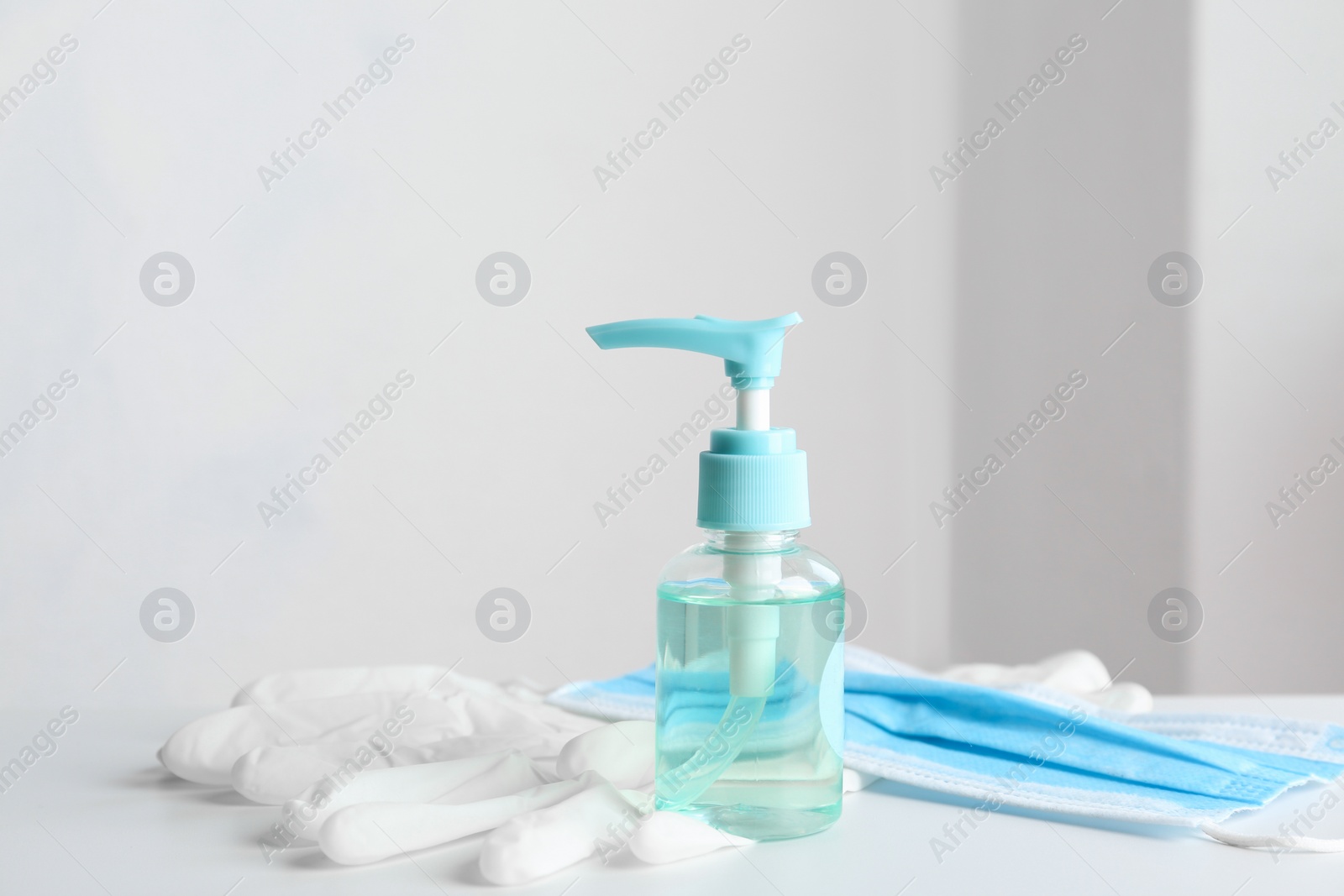 Photo of Antiseptic gel, protective gloves and mask on table indoors. Protection from virus