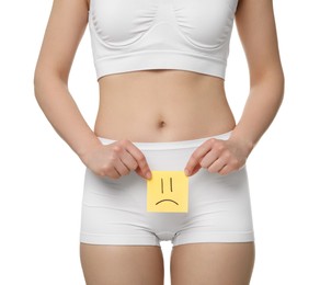 Photo of Cystitis. Woman holding sticky note with drawn sad face on white background, closeup