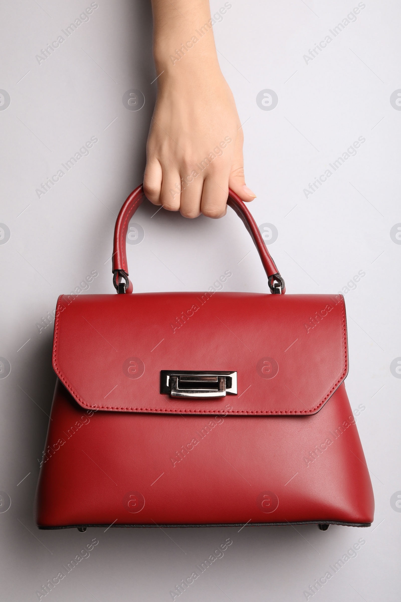 Photo of Woman holding small bag on light grey background, top view