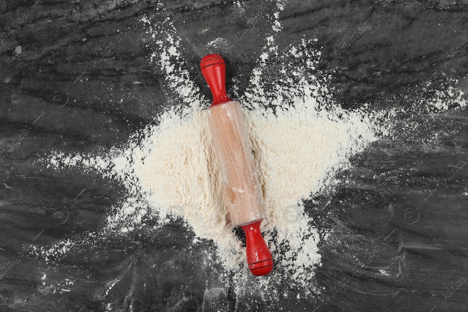 Photo of Flour and rolling pin on grey marble table, top view
