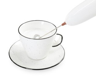 Whisking milk in cup with mini mixer (frother wand) isolated on white