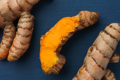 Raw turmeric roots on blue wooden table, flat lay