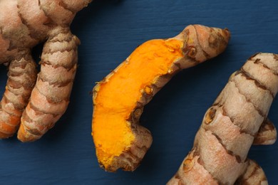 Photo of Raw turmeric roots on blue wooden table, flat lay