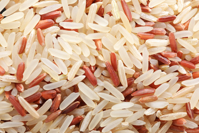 Photo of Mix of brown and polished rice as background, top view