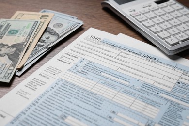 Photo of Payroll. Tax return forms, dollar banknotes and calculator on wooden table