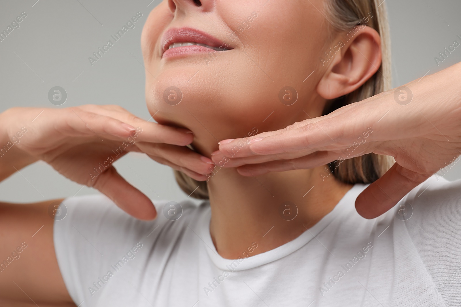 Photo of Mature woman touching her neck on grey background, closeup