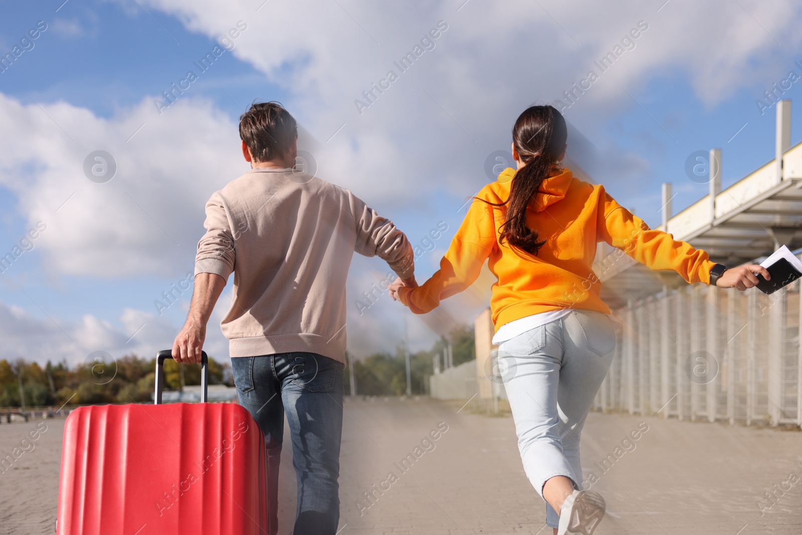 Image of Being late. Couple with suitcase running at station, back view. Motion blur effect