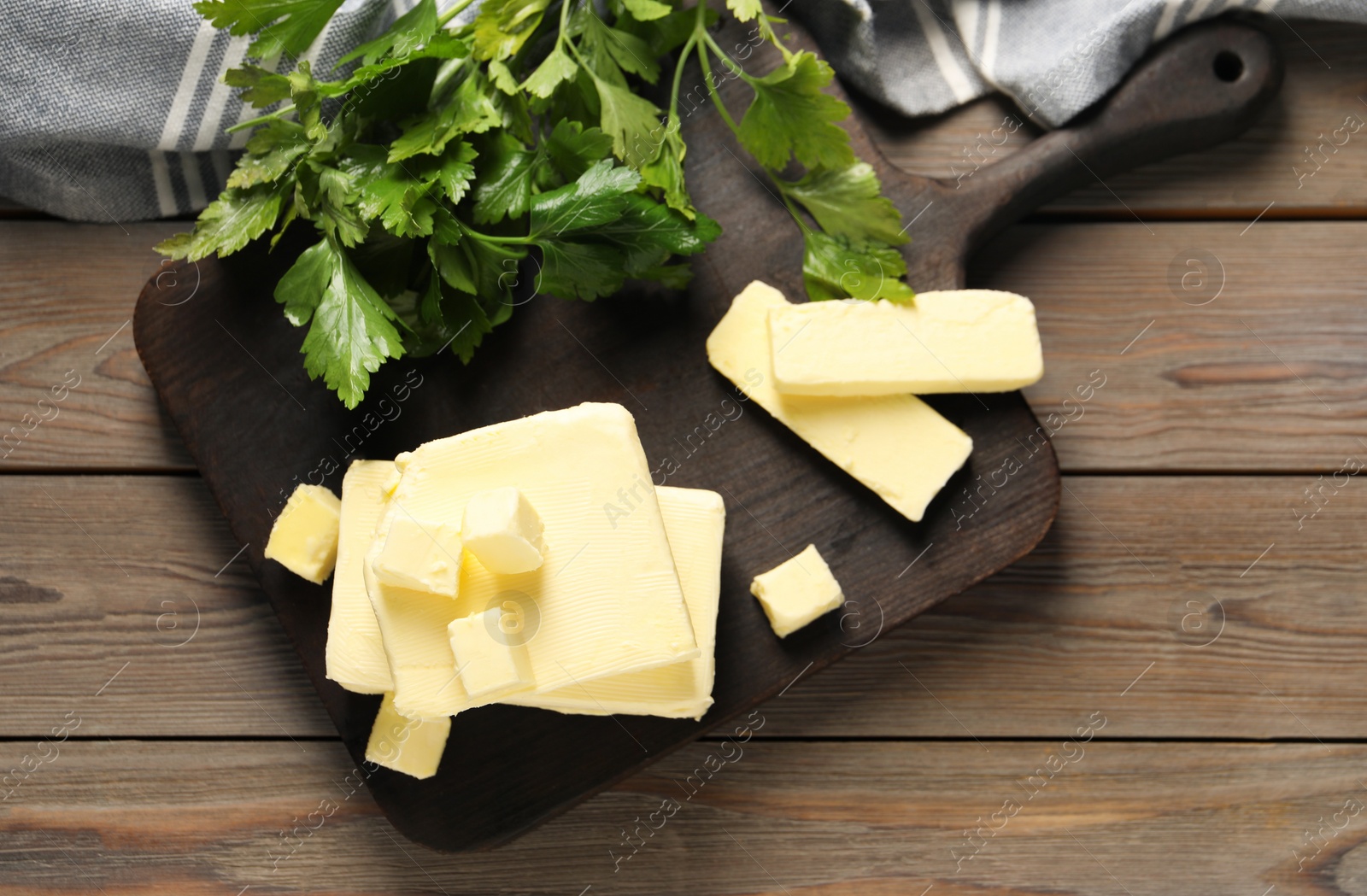 Photo of Tasty butter and parsley on wooden table, top view