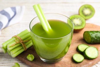 Glass of fresh celery juice on white wooden table, closeup