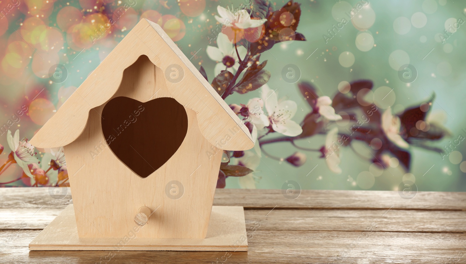 Image of Beautiful bird house on wooden table outdoors, space for text