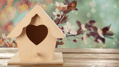 Beautiful bird house on wooden table outdoors, space for text