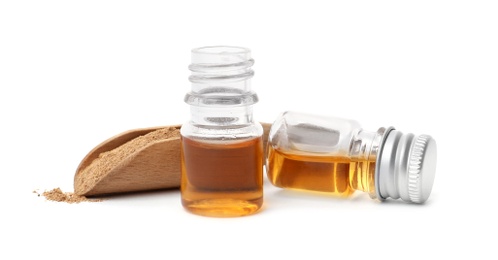 Bottles of cinnamon oil and scoop with powder on white background