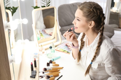 Photo of Portrait of beautiful woman applying makeup indoors