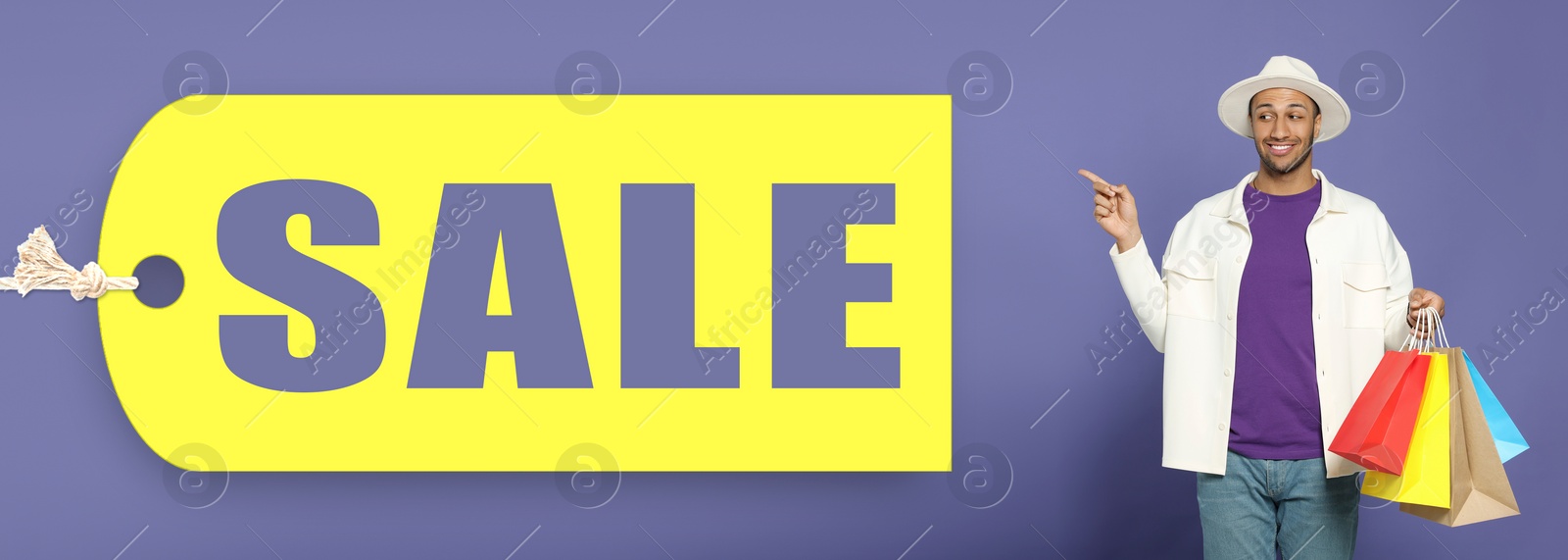 Image of Happy man with shopping bags pointing at Sale label on blue violet background, banner design