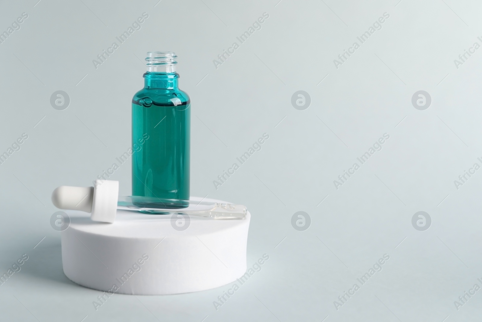 Photo of Bottle with cosmetic serum and pipette on light grey background, space for text