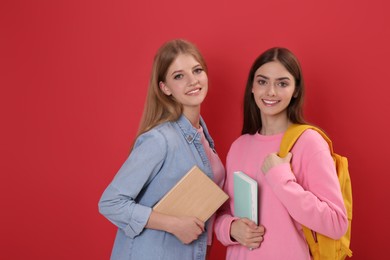 Teenage students with stationery and backpack on red background