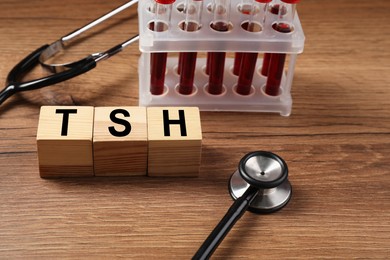 Photo of Endocrinology. Stethoscope, cubes with thyroid hormones and blood samples in test tubes on wooden table