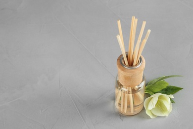 Photo of Aromatic reed freshener and flower on grey table, space for text